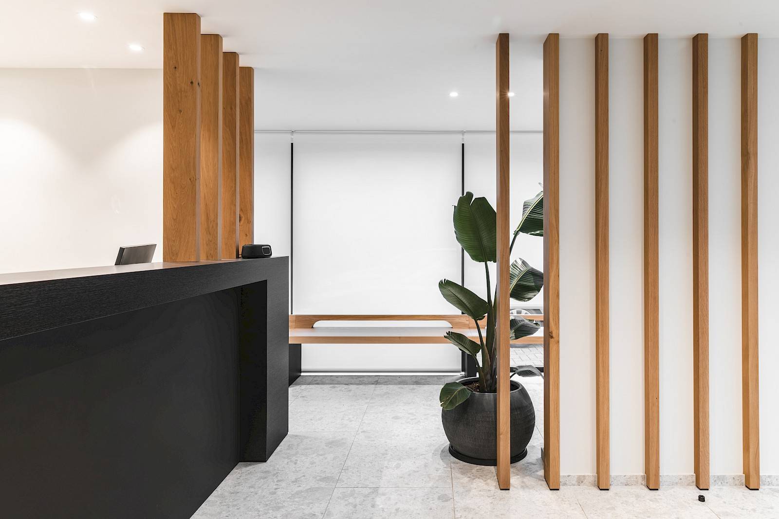 Inkomhal afgewerkt met hout en een plant door Zinder. 