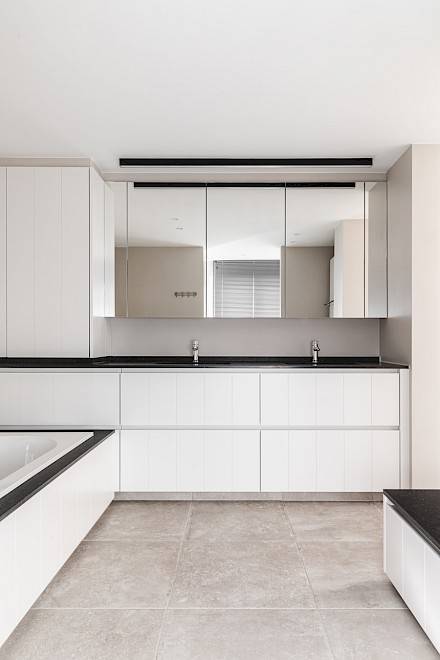 Badkamer: zicht op de twee lavabo's en de witte maatwerkkasten